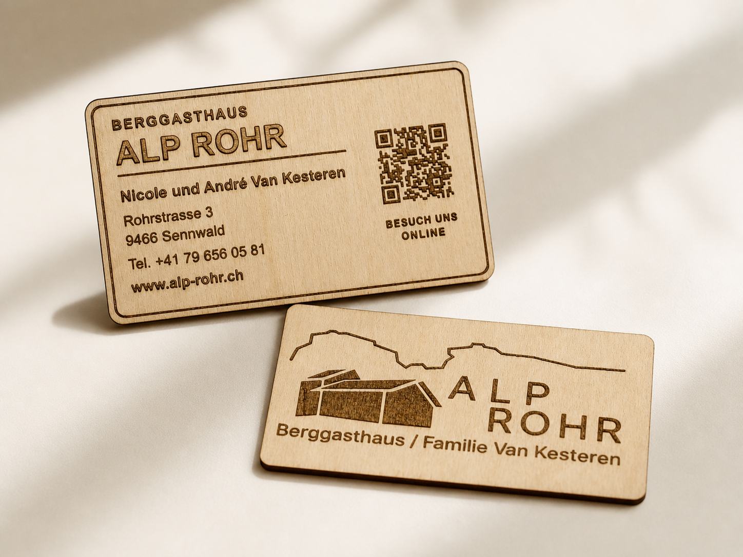 Front and back of personalized engraved birch business cards displayed together on a warm ivory surface